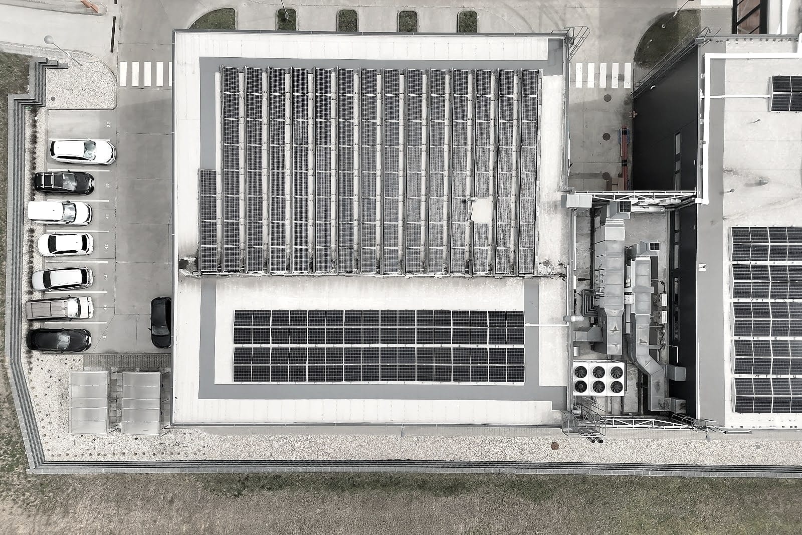 Senkrechtes Orthofoto einer Produktionshalle mit Photovoltaik auf dem Dach, Parkplatz und Schutzdach