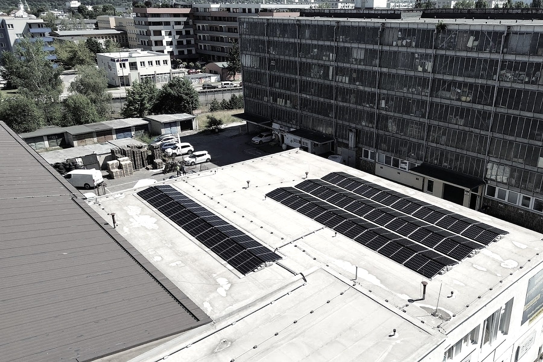 Orthofoto eines Flachdachs mit PV-Anlage in Žilina (Slowakei), Parkplatz und Nachbargebäude